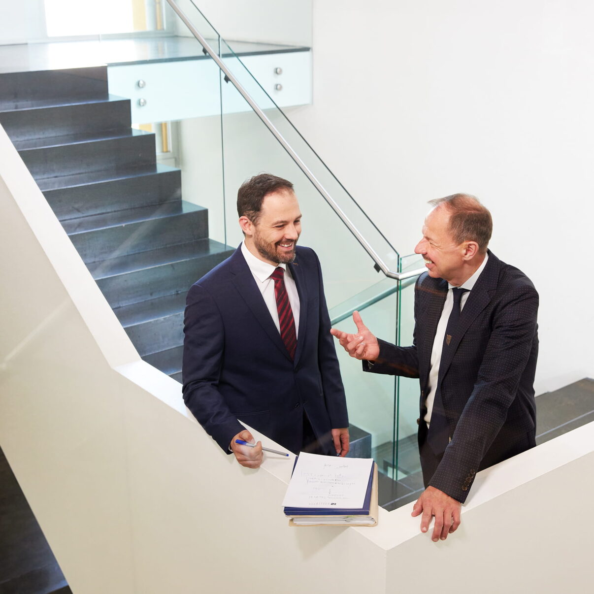 Zwei Mitglieder des Insolvenzrechtsteams besprechen Unterlagen in einem Treppenaufgang.