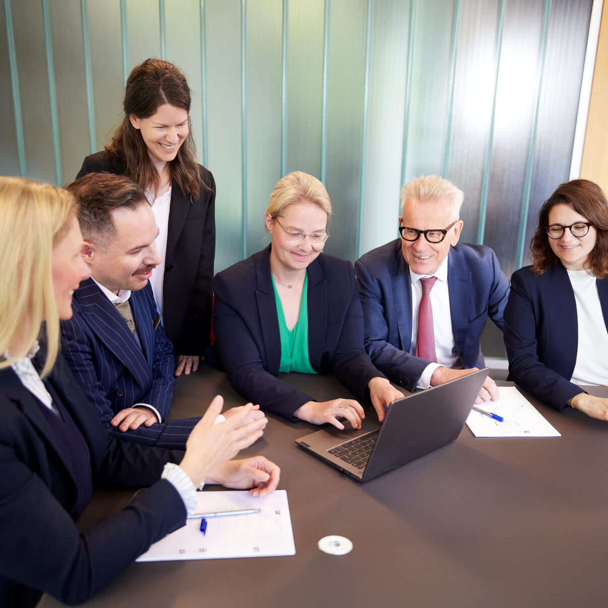 Sechs Teammitglieder des M&A-Teams bei einer gemeinsamen Projektbesprechung am Konferenztisch.