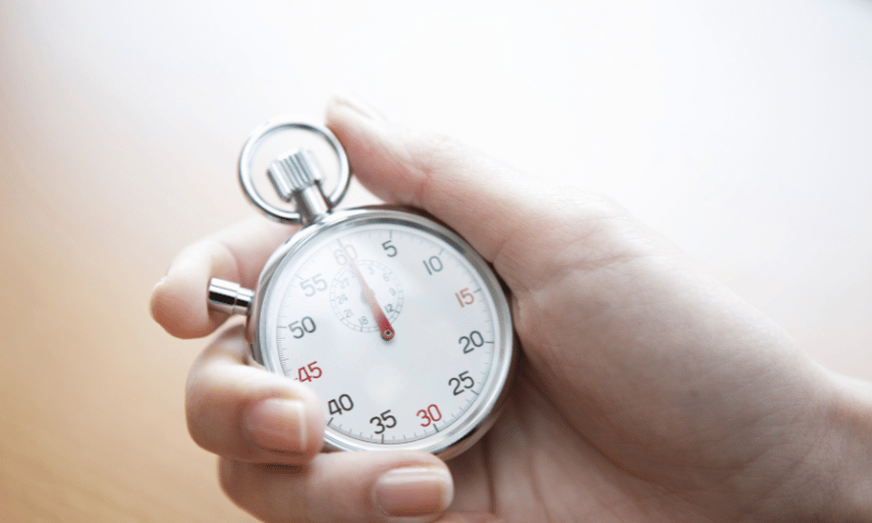 Stoppuhr in einer Hand als Symbol für Fristen, Zeitdruck und die einjährige Präklusivfrist im Recht.
